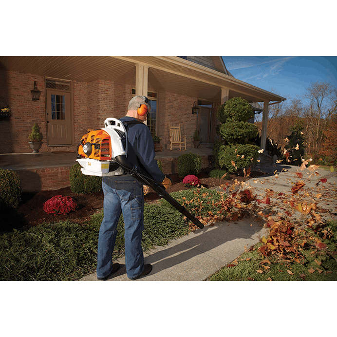 Man standing in front of house using the BR 350 to blow leaves off the sidewalk