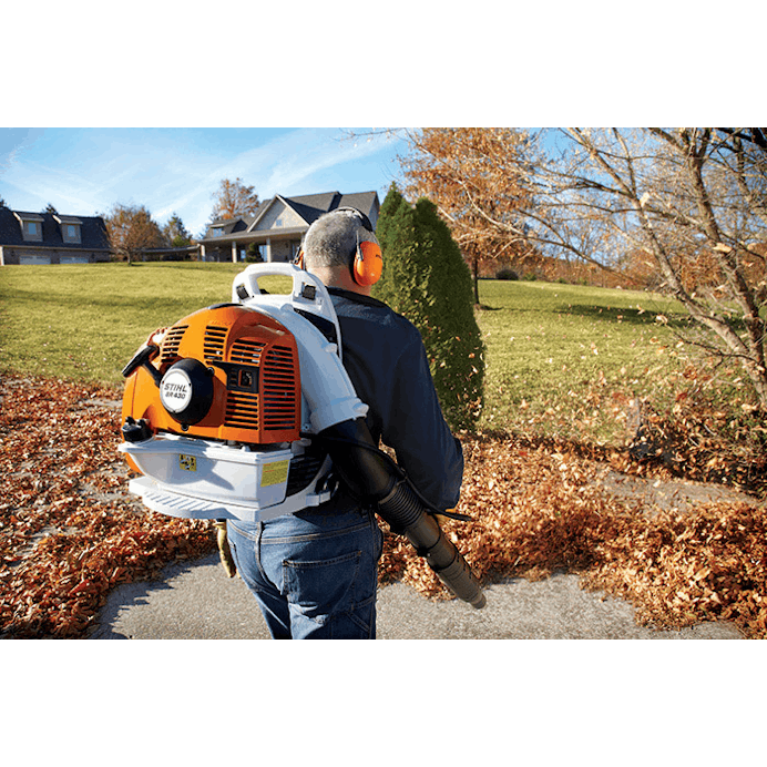 Man in STIHL protective gear using the BR 430 to blow leaves off the pavement