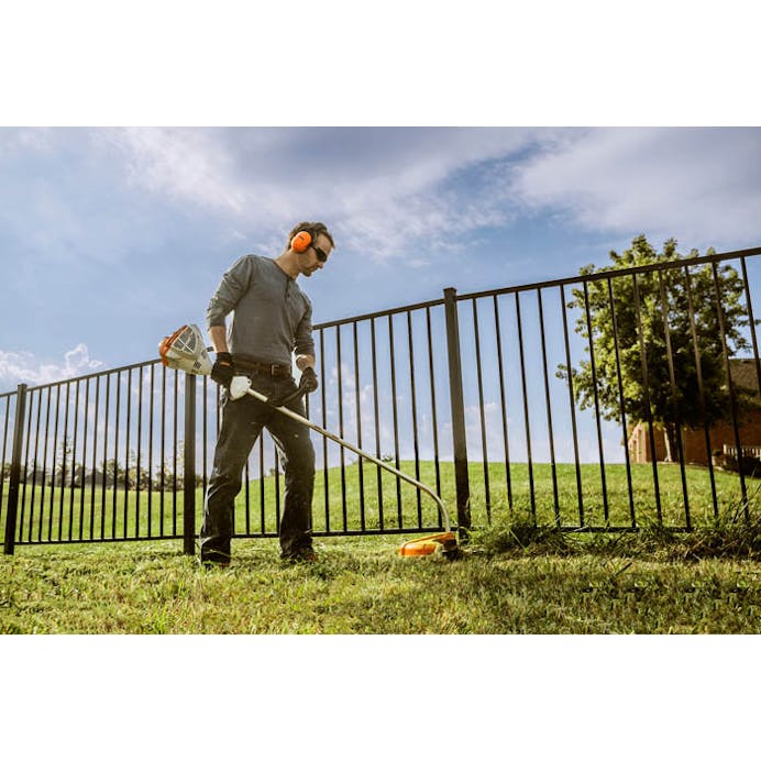 Man using STIHL FS 50 C-E to trim along fence line