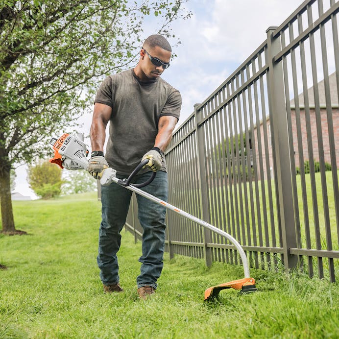 Man trimming along fence line using the FS 38