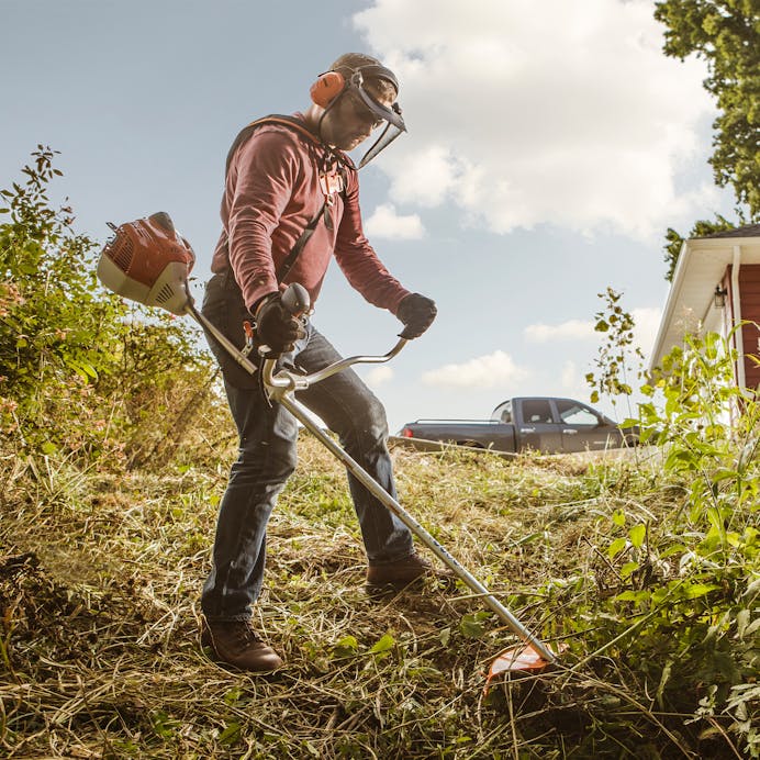 Man trimming land beside house using the STIHL FS 240