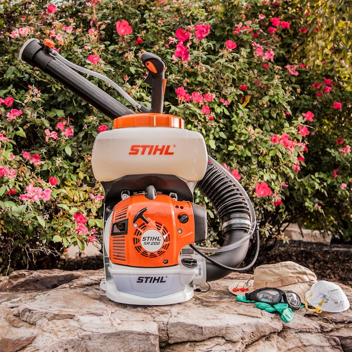 SR 200 in front of a flowery bush next to STIHL protective apparel 