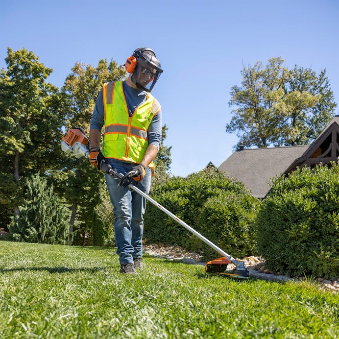 Man in STIHL protective gear trimming lawn with FS 94 R