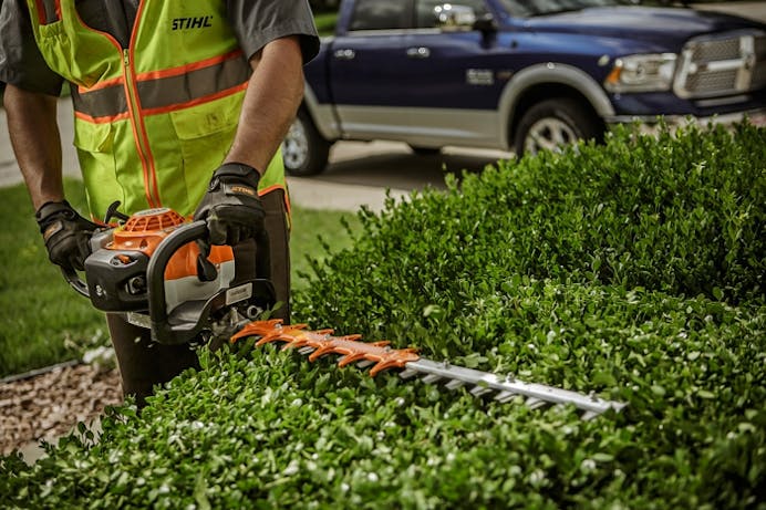 Close up of man using the HS 82 R to trim hedge
