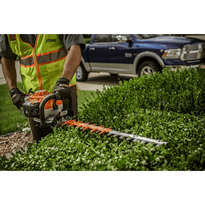 Close up of man using the HS 82 R to trim hedge