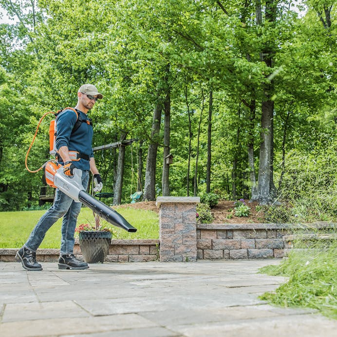 Man blowing grass clippings using the BGA 100 with AR 3000 L Backpack Battery