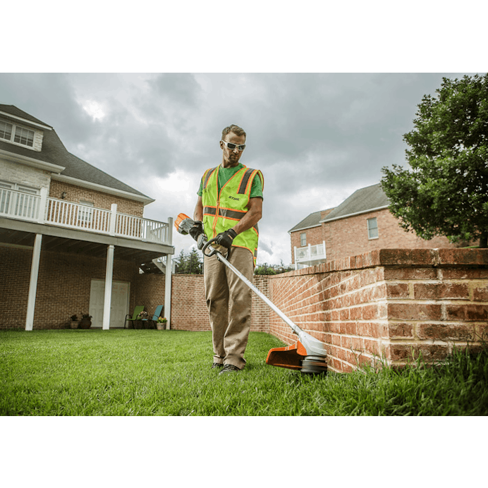Man in STIHL Reflective Safety Vest trimming along brick wall with the FSA 90 R