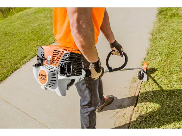 Back view of man using FC 96 to clean up lawn's edge