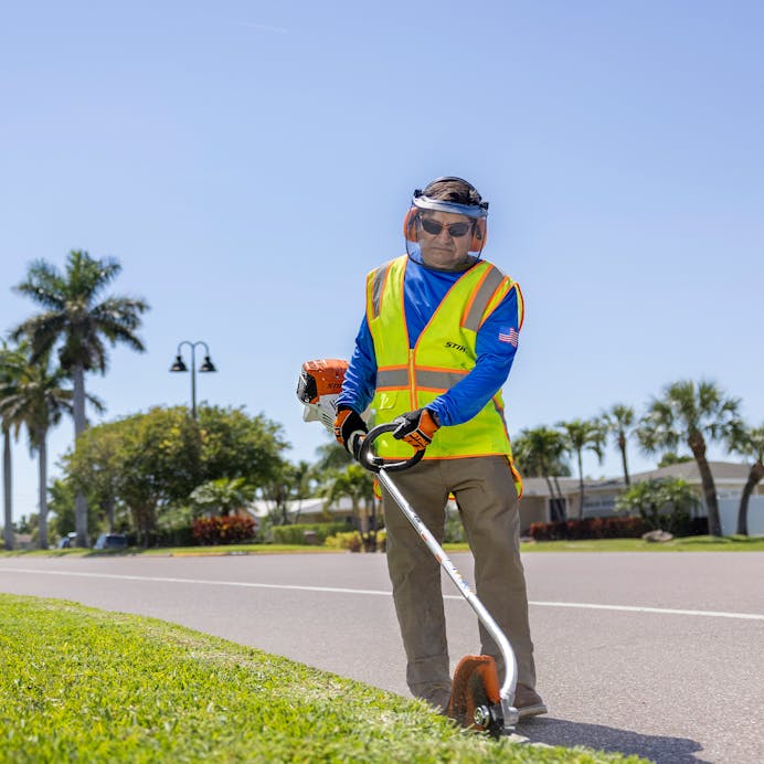 Man using STIHL FC 91 on edge of sidewalk