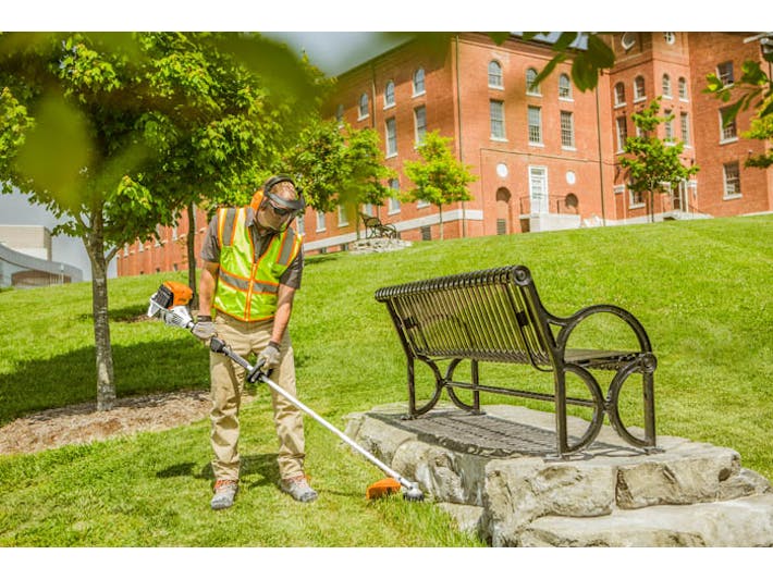 Man in STIHL Reflective Safety Vest trimming alongside bench using the FS 91 R