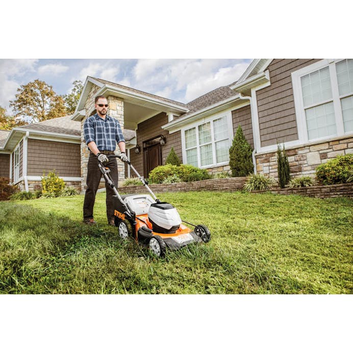 Man mowing lawn in front of house with the STIHL RMA 510