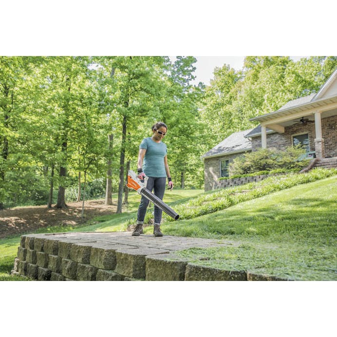 Woman blowing grass clippings off stone using the BGA 45