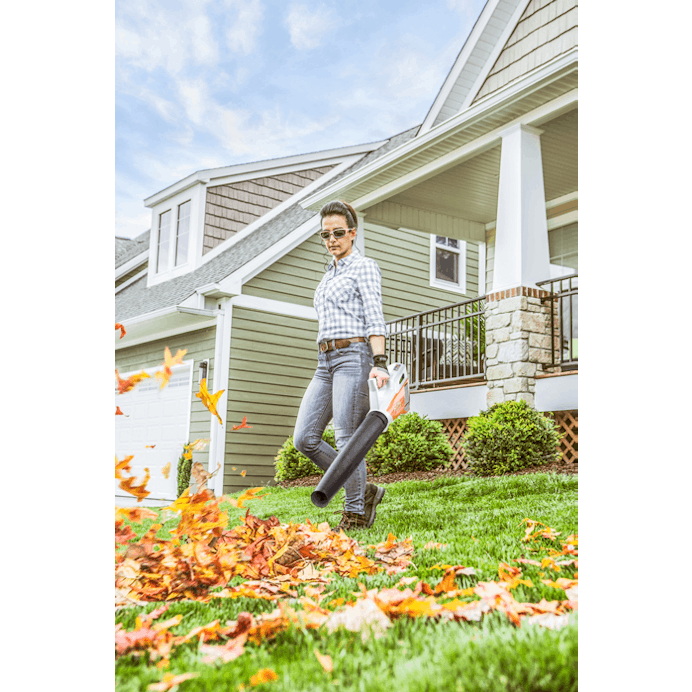 Woman blowing leaves outside house using the BGA 45