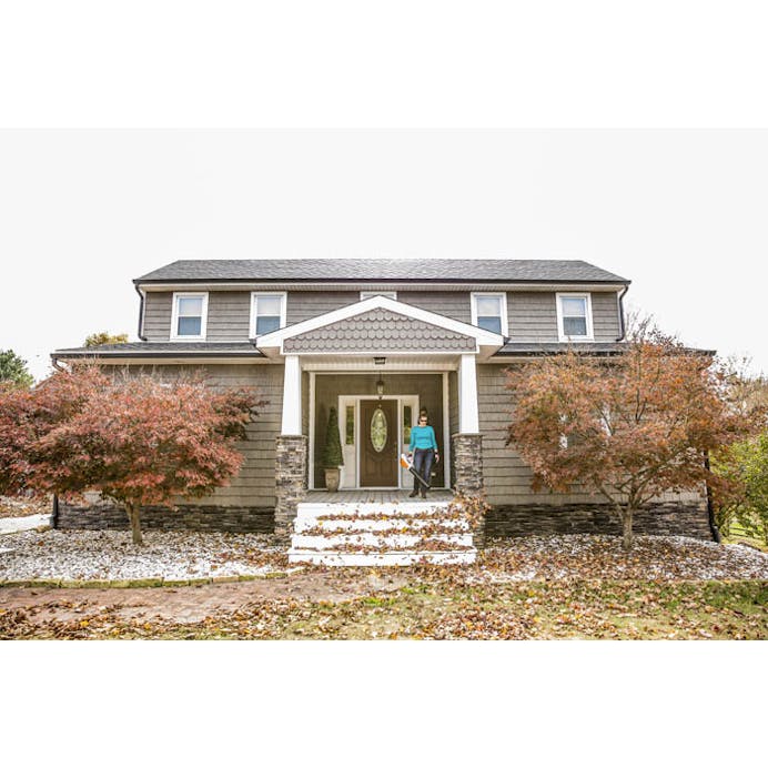 Wide shot of woman blowing leaves outside of house using the BGA 45