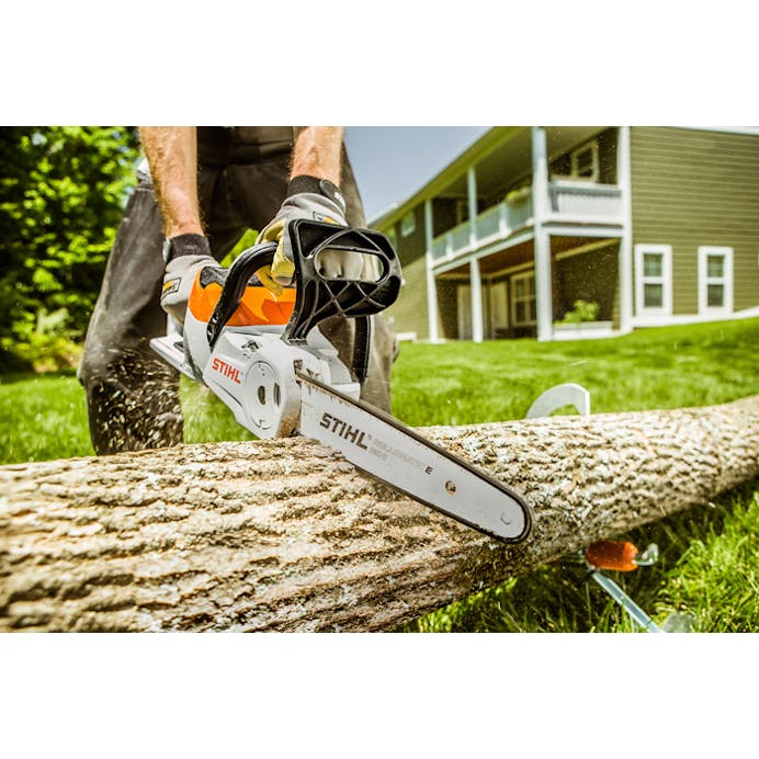 A man holding MSA 120 Chainsaw cutting a log 