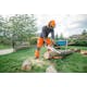 Man cutting log with MSA 120 chainsaw in side yard