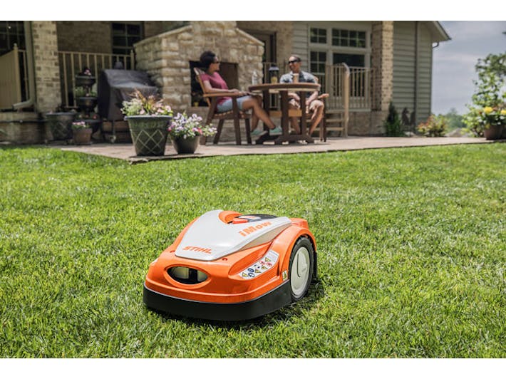 iMOW® RMI 422 PC-L mowing yard while people lounge on the patio 