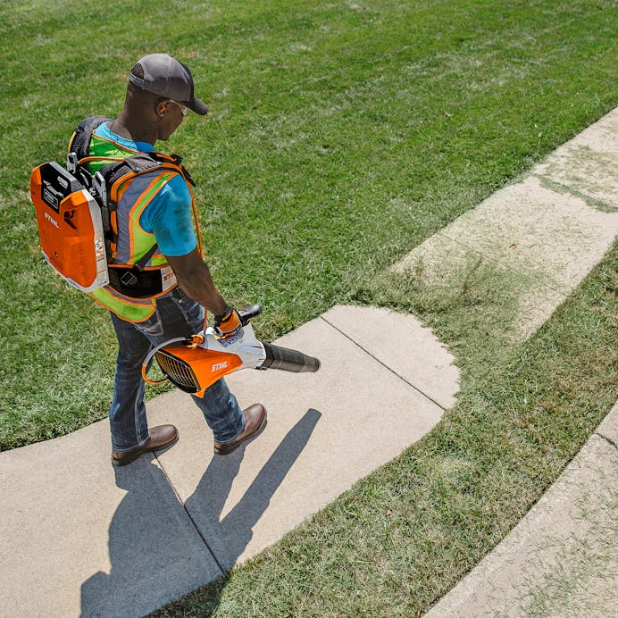 Man blowing grass clippings in driveway with the BGA 200