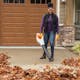 Woman using BGA 86 to blow leaves off of driveway