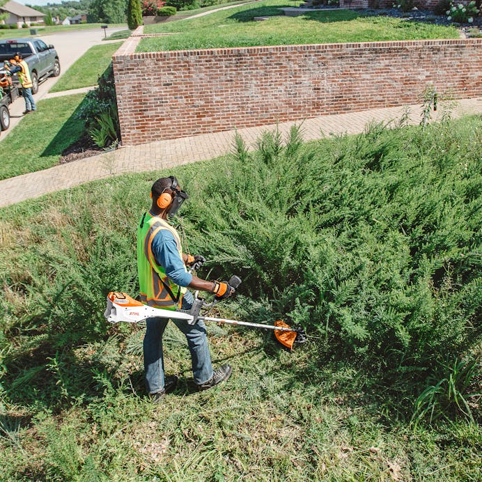 Man trimming along bushes with STIHL FSA 135