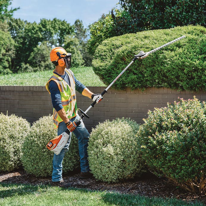 Man using HLA 135 (145°) to trim hedges in STIHL PPE