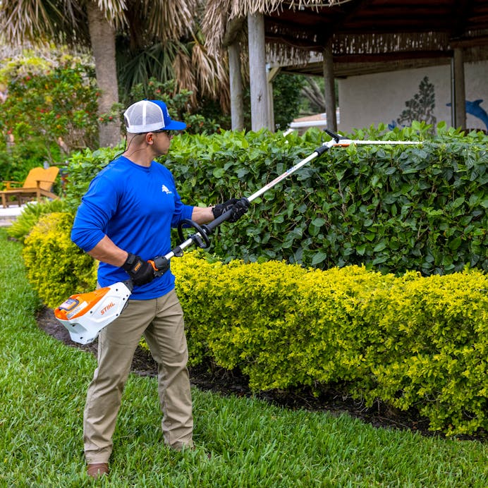 Man using HLA 135 (145°) to trim top of the hedges with sideways blade