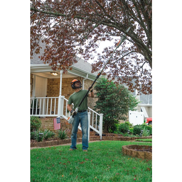 Man using the HTA 50 to cut branches on tree in front yard