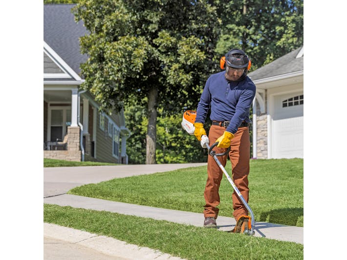 	Man using FCA to edge sidewalk grass in STIHL PPE