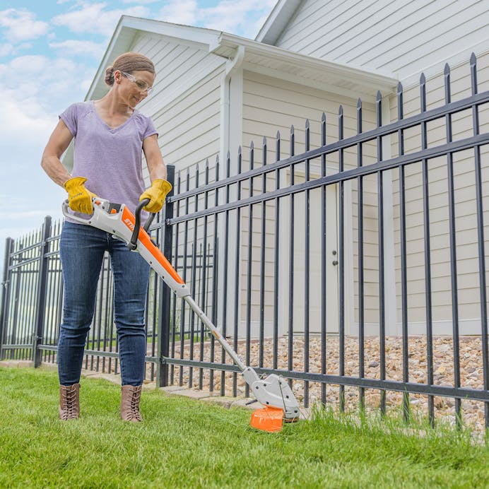 Woman trimming grass along fence with STIHL FSA 30