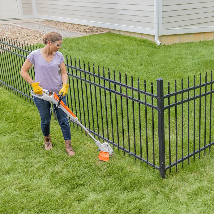 Woman trimming grass along fence with STIHL FSA 30