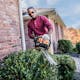 Man trimming hedges on side of house with the HS 45