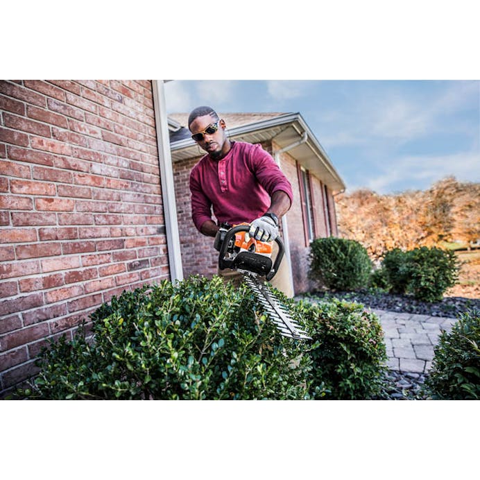 Man trimming bushes on side of house using the HS 45 