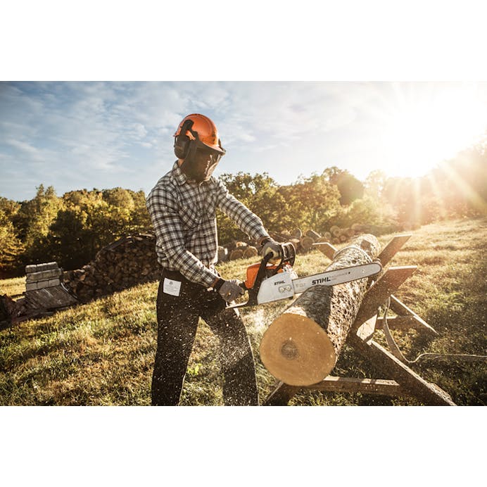 Man cutting a log with the MS 170 Chainsaw with the sun blazing in the background