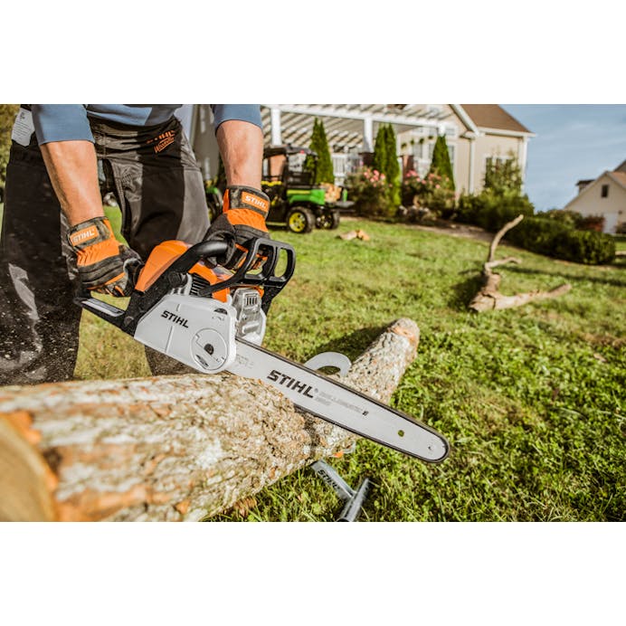 Side view of STIHL MS 180 C-BE Chainsaw cutting log in a backyard