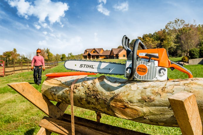 Man walking up to MS 250 Chainsaw resting on a log