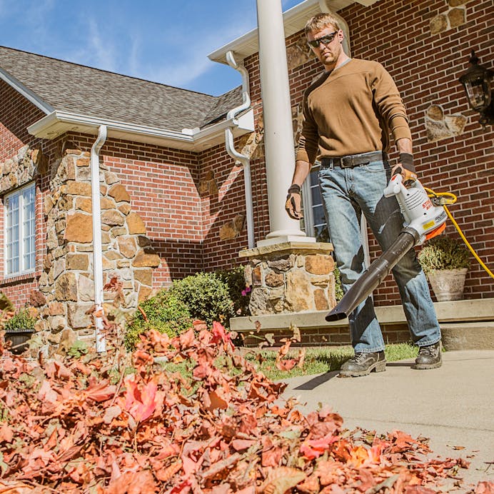 Man blowing leaves off sidewalk in front of house with the BGE 61