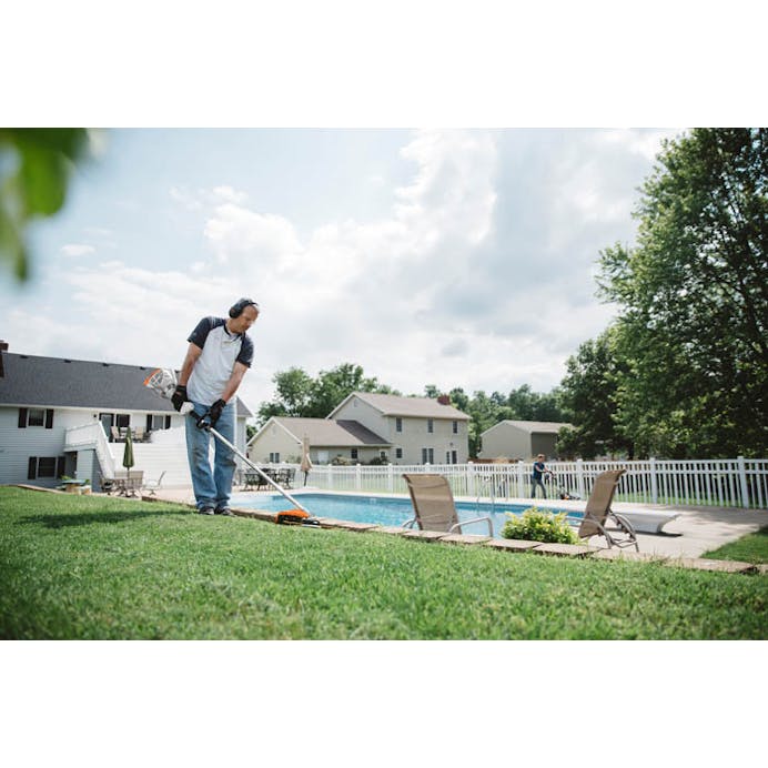 Man trimming along side of pool