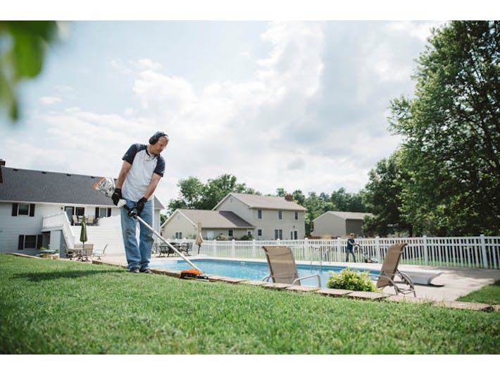 Man trimming along side of pool