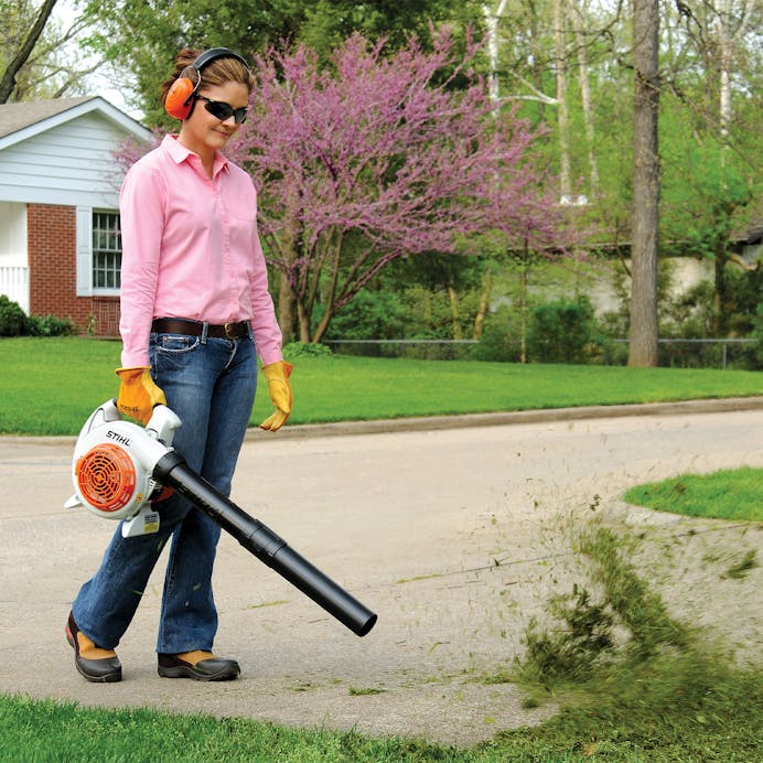 Woman using BG 86 C-E to clear grass clippings from sidewalk