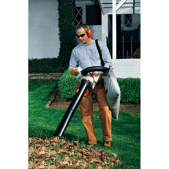Man picking up leaves in yard with the SH 56 C-E
