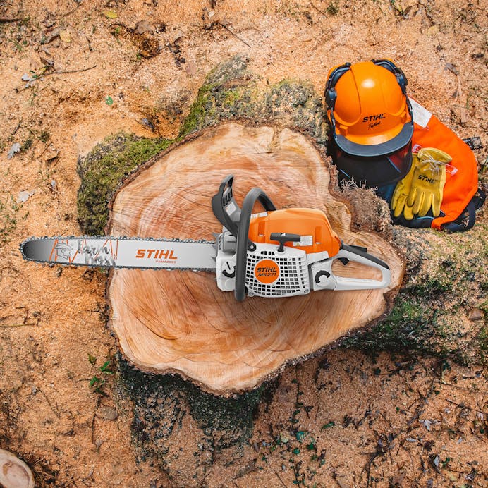 View from above of a MS 271 FARM BOSS® resting on a tree stump next to some STIHL protective wear